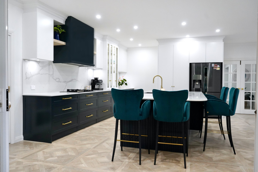 Design ideas for a large transitional galley open plan kitchen in Sydney with an undermount sink, shaker cabinets, black cabinets, quartz benchtops, white splashback, engineered quartz splashback, black appliances, light hardwood floors, with island, brown floor and white benchtop.