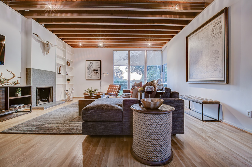 Inspiration for a large eclectic open concept living room in Dallas with white walls, light hardwood floors, a standard fireplace, a tile fireplace surround and a wall-mounted tv.