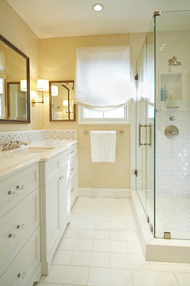 Design ideas for a mid-sized traditional 3/4 bathroom in Los Angeles with recessed-panel cabinets, white cabinets, a corner shower, white tile, stone tile, yellow walls, marble floors, an undermount sink and marble benchtops.