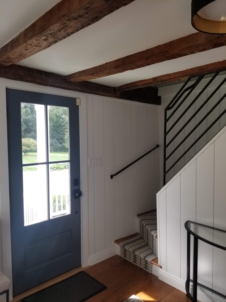 Kleines Foyer mit grauer Wandfarbe, braunem Holzboden, Einzeltür, grauer Haustür, braunem Boden und freigelegten Dachbalken in New York