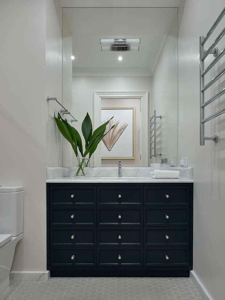 Mid-sized transitional powder room in Moscow with blue cabinets, gray tile, marble benchtops, recessed-panel cabinets, a two-piece toilet, an undermount sink and grey floor.
