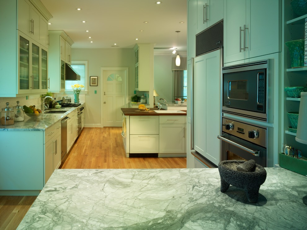 Example of a mid-sized transitional u-shaped enclosed kitchen design in Raleigh with recessed-panel cabinets, green cabinets, marble countertops, stainless steel appliances and an island