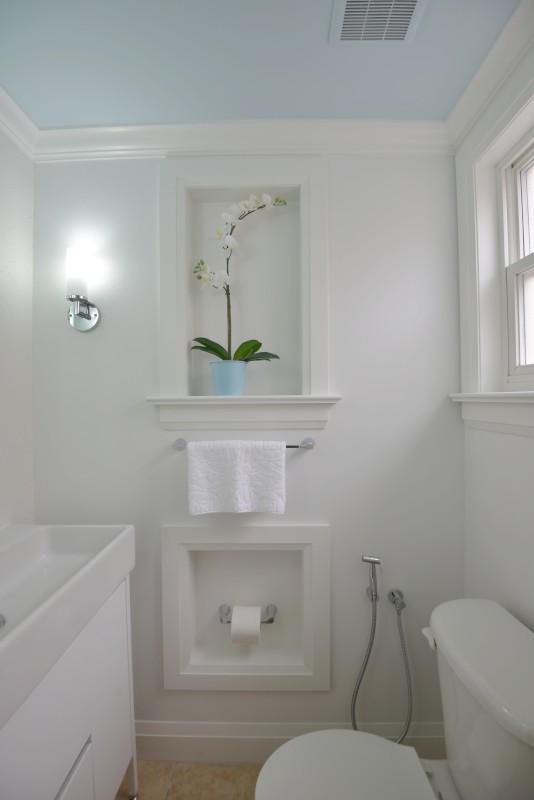 This is an example of a small transitional powder room in Toronto with white tile, porcelain tile, white walls, flat-panel cabinets, white cabinets, a one-piece toilet, porcelain floors and a pedestal sink.