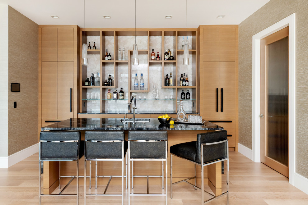 Design ideas for a large contemporary seated home bar in Other with an undermount sink, light wood cabinets, white splashback, stone slab splashback, light hardwood floors, beige floor, black benchtop and open cabinets.