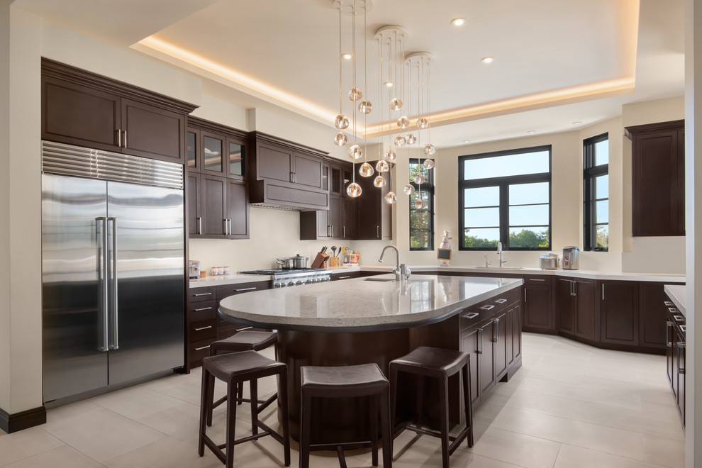 Transitional u-shaped kitchen in San Francisco with recessed-panel cabinets, dark wood cabinets, white splashback, stainless steel appliances, porcelain floors, white benchtop, with island and grey floor.