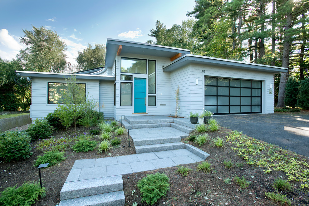 Photo of a mid-sized midcentury one-storey white house exterior in Boston with a flat roof and vinyl siding.