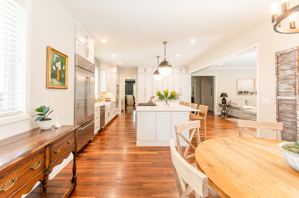 Open concept kitchen - large transitional l-shaped dark wood floor and brown floor open concept kitchen idea in Denver with a farmhouse sink, shaker cabinets, beige cabinets, quartz countertops, beige backsplash, ceramic backsplash, stainless steel appliances, an island and white countertops