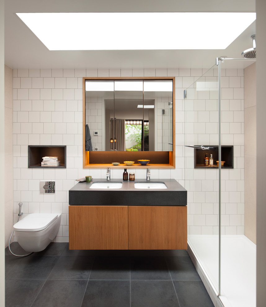 Contemporary bathroom in London with flat-panel cabinets, medium wood cabinets, an alcove shower, white tile, white walls, an undermount sink, grey floor, an open shower and grey benchtops.