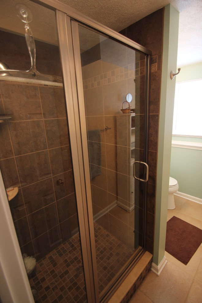 Inspiration for a mid-sized traditional bathroom in Cleveland with glass-front cabinets, white cabinets, an alcove shower, brown tile, green walls and an undermount sink.