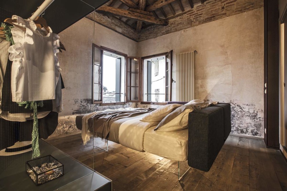 This is an example of an industrial master bedroom in Venice with dark hardwood floors, brown floor and no fireplace.