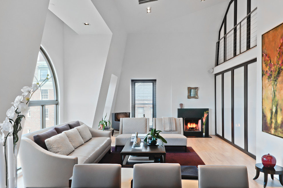This is an example of a contemporary formal open concept living room in Boston with white walls, light hardwood floors, a standard fireplace, no tv and beige floor.