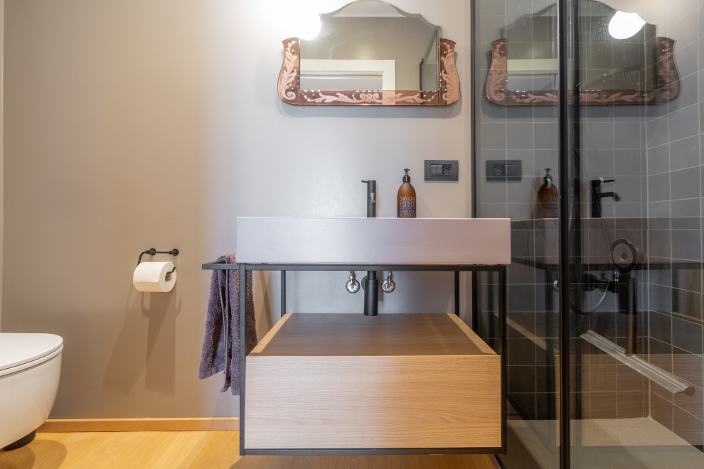 Immagine di un piccolo bagno di servizio minimal con ante lisce, ante in legno chiaro, WC a due pezzi, pareti grigie, pavimento in legno verniciato, lavabo rettangolare e mobile bagno sospeso