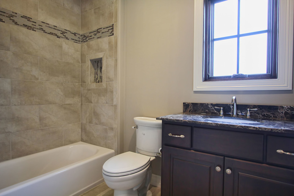 Design ideas for a small traditional bathroom in Louisville with an integrated sink, raised-panel cabinets, dark wood cabinets, granite benchtops, a shower/bathtub combo, a two-piece toilet, beige tile, ceramic tile, beige walls and ceramic floors.