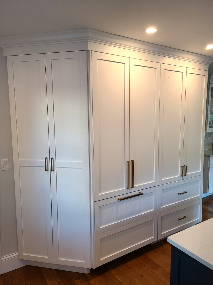 Large transitional u-shaped medium tone wood floor eat-in kitchen photo in Boston with recessed-panel cabinets, white cabinets, an island and white countertops