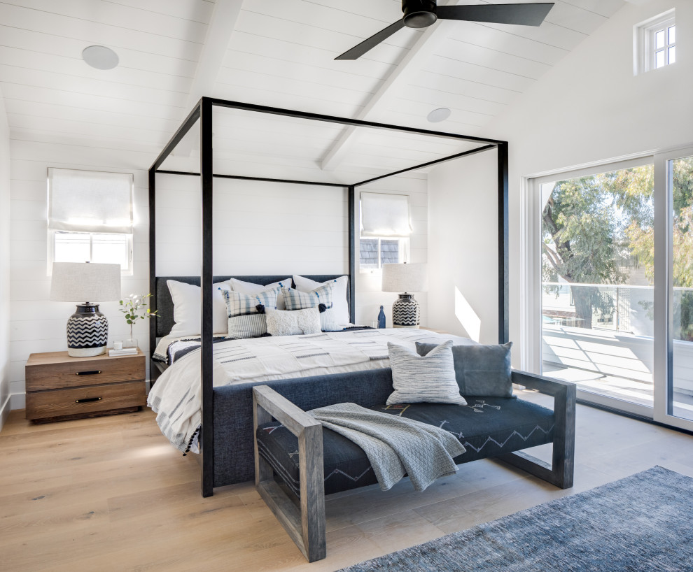 Photo of a large beach style master bedroom in Orange County with white walls, light hardwood floors, no fireplace and beige floor.