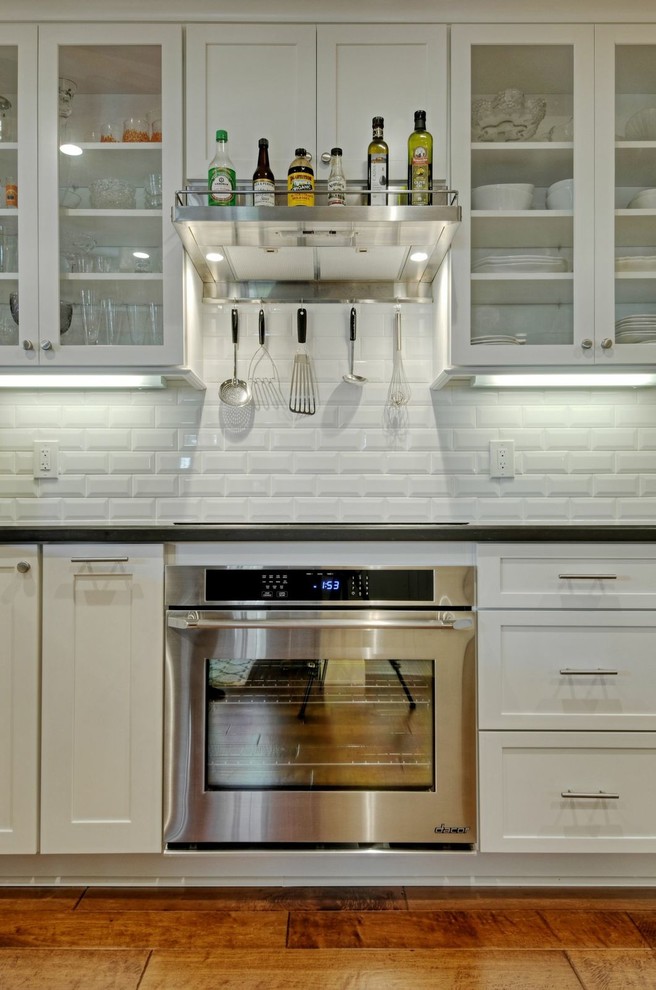 Mid-sized transitional galley medium tone wood floor open concept kitchen photo with a farmhouse sink, shaker cabinets, white cabinets, quartz countertops, white backsplash, ceramic backsplash, stainless steel appliances and no island