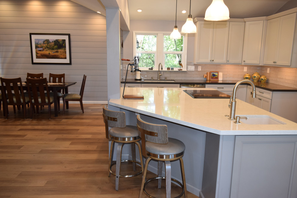 Design ideas for a mid-sized transitional l-shaped eat-in kitchen in Sacramento with an undermount sink, shaker cabinets, white cabinets, quartz benchtops, grey splashback, ceramic splashback, stainless steel appliances, vinyl floors, with island, brown floor, grey benchtop and vaulted.