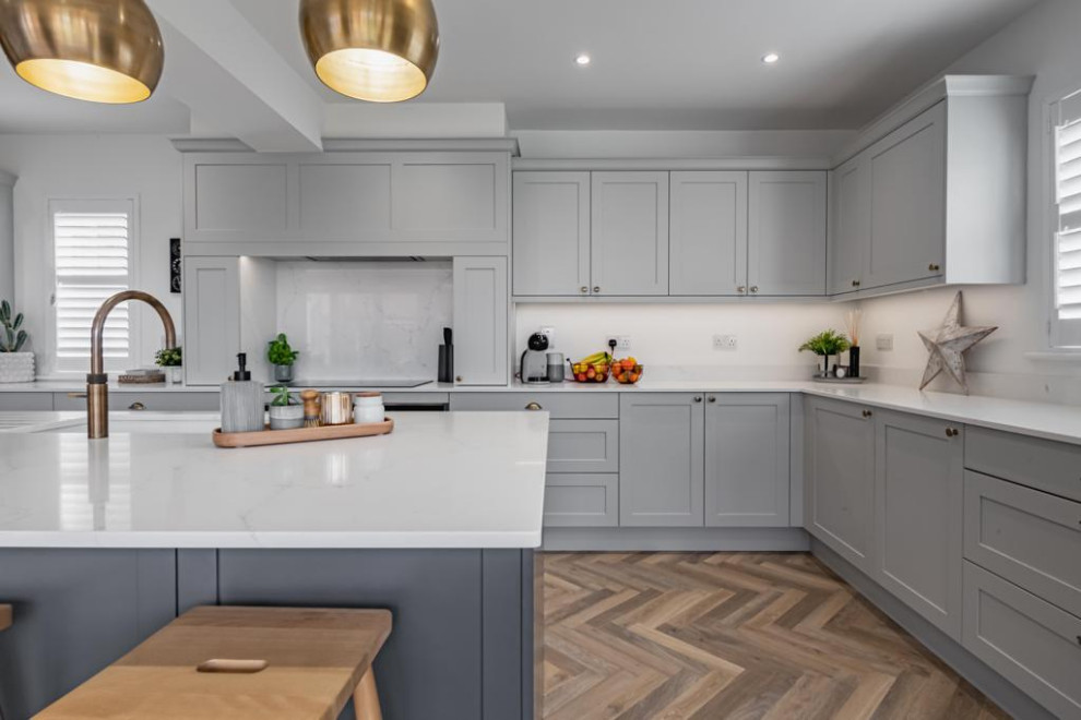 Inspiration for a large modern l-shaped kitchen/diner in Other with a submerged sink, shaker cabinets, blue cabinets, quartz worktops, white splashback, stainless steel appliances, an island, brown floors and white worktops.