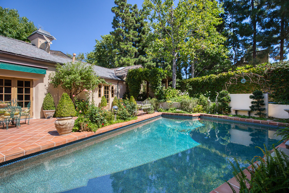 Photo of an expansive country courtyard custom-shaped pool in Orange County with a water feature and tile.