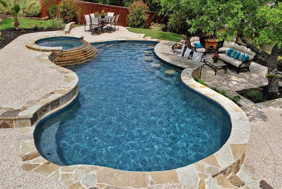 This is an example of a mid-sized traditional backyard custom-shaped pool in Austin with a hot tub and gravel.