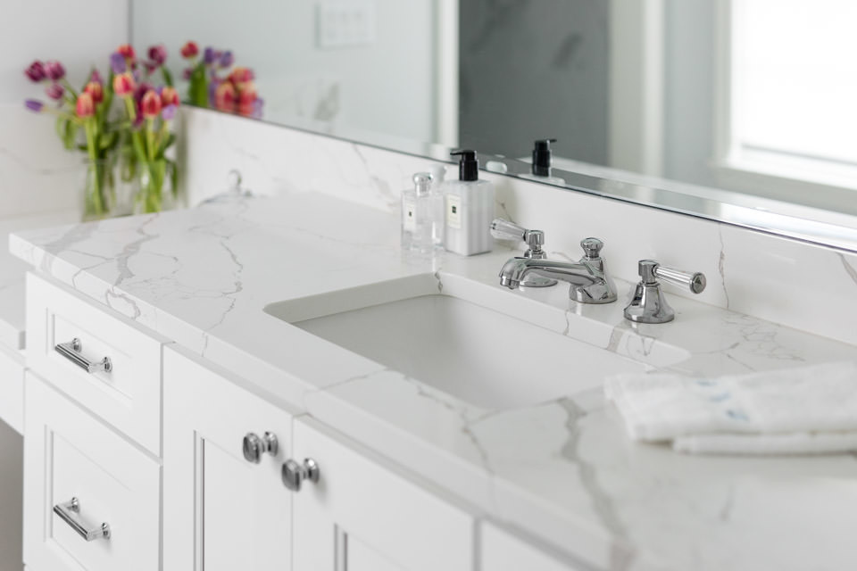 The master vanity of Engineered Quartz is elegant and durable, large enough to display personal items and still drops down to a seated vanity. The Newport Brass chrome faucet is classic and clean, com