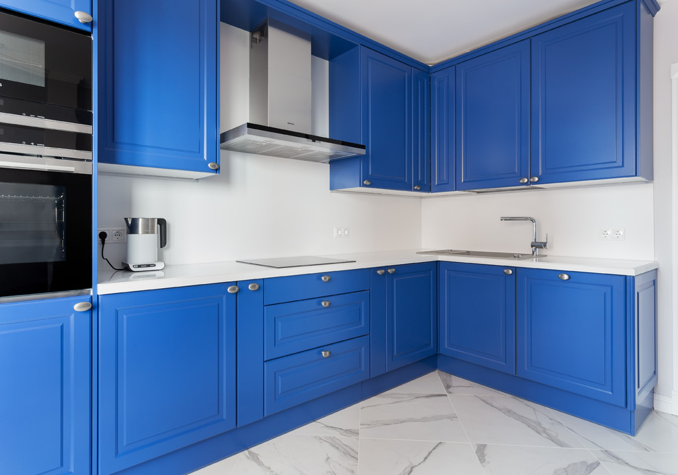 Mid-sized contemporary l-shaped separate kitchen in Moscow with a drop-in sink, raised-panel cabinets, blue cabinets, quartz benchtops, white splashback, stone slab splashback, black appliances, marble floors, no island, white floor and white benchtop.