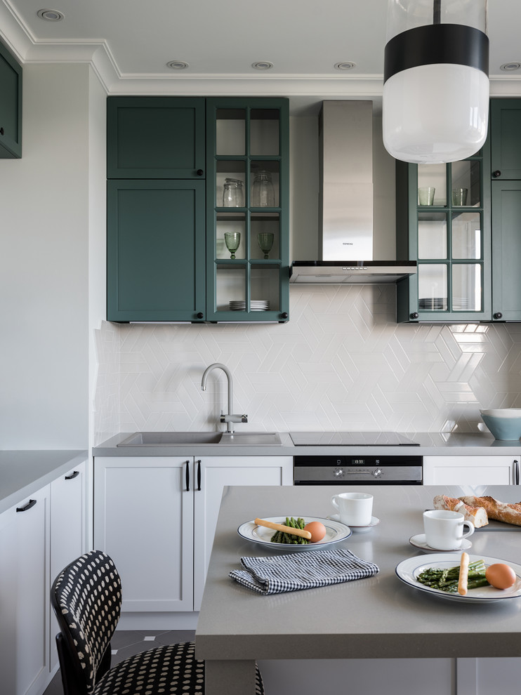 Inspiration for a small transitional l-shaped separate kitchen in Moscow with an undermount sink, recessed-panel cabinets, green cabinets, solid surface benchtops, grey splashback, ceramic splashback, stainless steel appliances, ceramic floors, with island, grey floor and grey benchtop.
