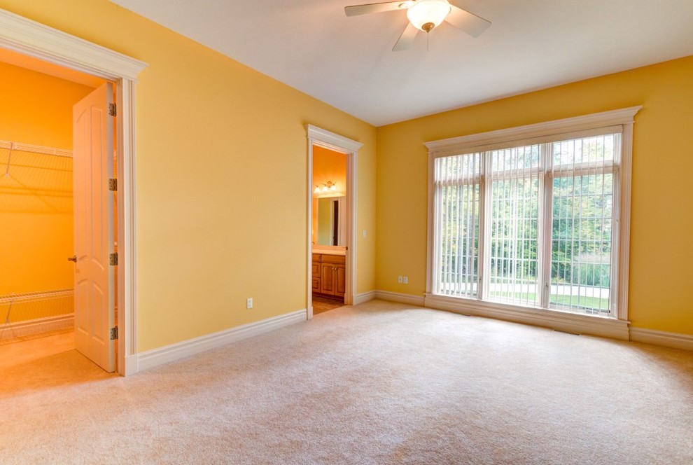 Traditional bedroom in Cleveland with yellow walls and carpet.