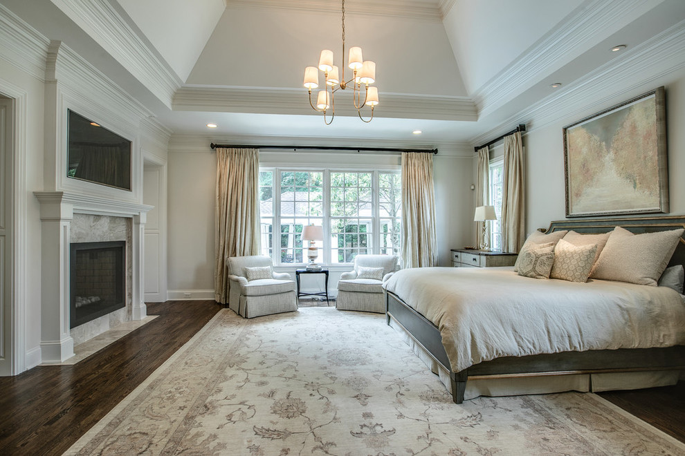 Design ideas for a large traditional master bedroom in Nashville with beige walls, dark hardwood floors, a two-sided fireplace, a wood fireplace surround and brown floor.