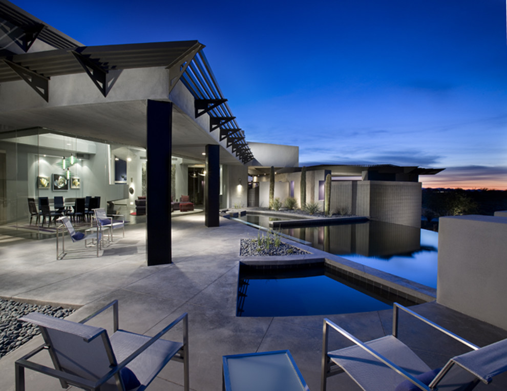 This is an example of a large modern backyard custom-shaped infinity pool in Phoenix with a hot tub and concrete slab.