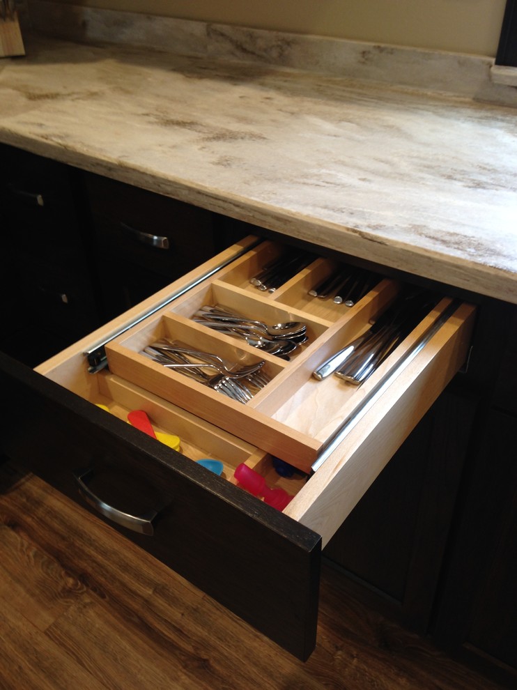 Example of a mid-sized mountain style kitchen design with an integrated sink, flat-panel cabinets, dark wood cabinets, solid surface countertops, stainless steel appliances and a peninsula