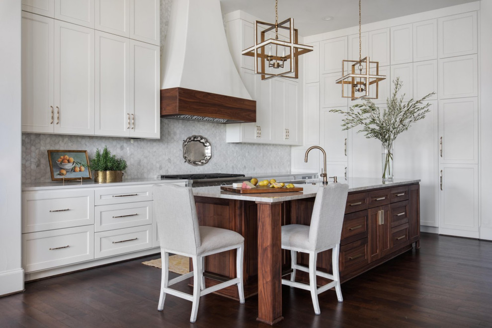 Example of a mid-sized transitional l-shaped medium tone wood floor and brown floor enclosed kitchen design in Austin with an undermount sink, shaker cabinets, white cabinets, quartzite countertops, white backsplash, marble backsplash, stainless steel appliances, an island and beige countertops