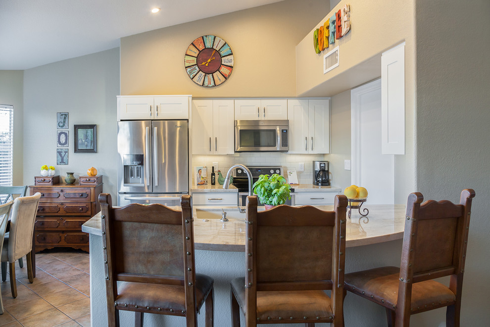 Example of a transitional galley ceramic tile open concept kitchen design in Phoenix with an undermount sink, recessed-panel cabinets, white cabinets, quartz countertops, white backsplash, ceramic backsplash, stainless steel appliances and an island