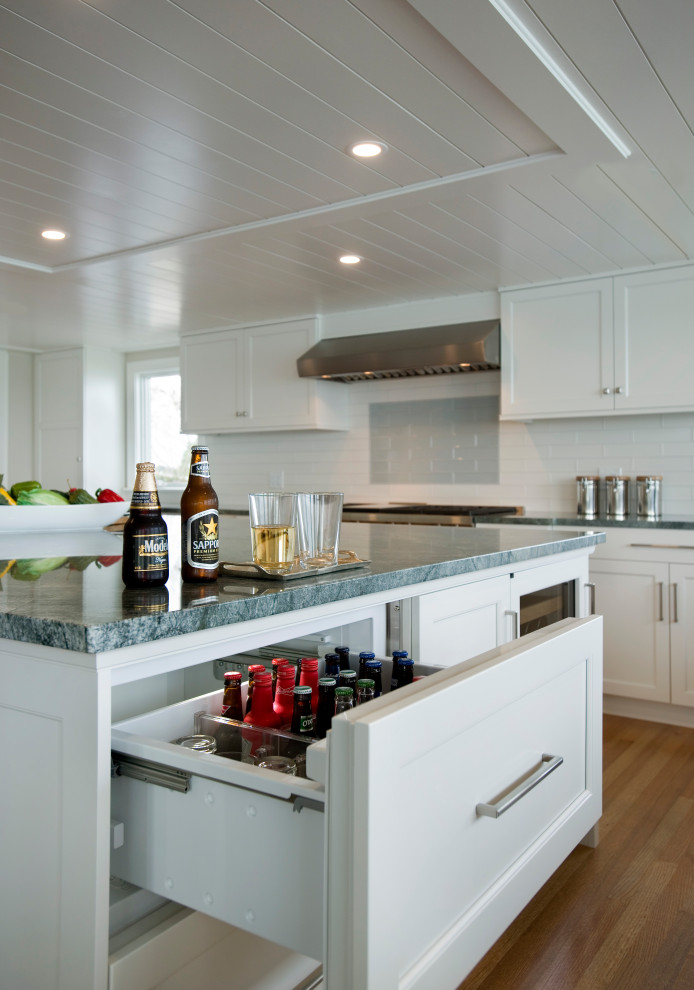 Inspiration for an expansive beach style u-shaped eat-in kitchen in Boston with an undermount sink, recessed-panel cabinets, white cabinets, quartzite benchtops, multi-coloured splashback, cement tile splashback, panelled appliances, light hardwood floors, with island and green benchtop.