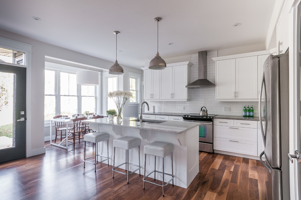 Design ideas for a mid-sized l-shaped eat-in kitchen in Toronto with an undermount sink, beaded inset cabinets, white cabinets, white splashback, subway tile splashback, stainless steel appliances, medium hardwood floors and with island.