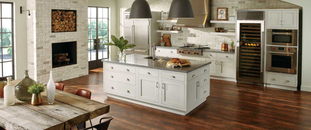 Mid-sized transitional single-wall dark wood floor and brown floor enclosed kitchen photo in Orange County with an undermount sink, shaker cabinets, white cabinets, granite countertops, white backsplash, subway tile backsplash, stainless steel appliances, an island and gray countertops