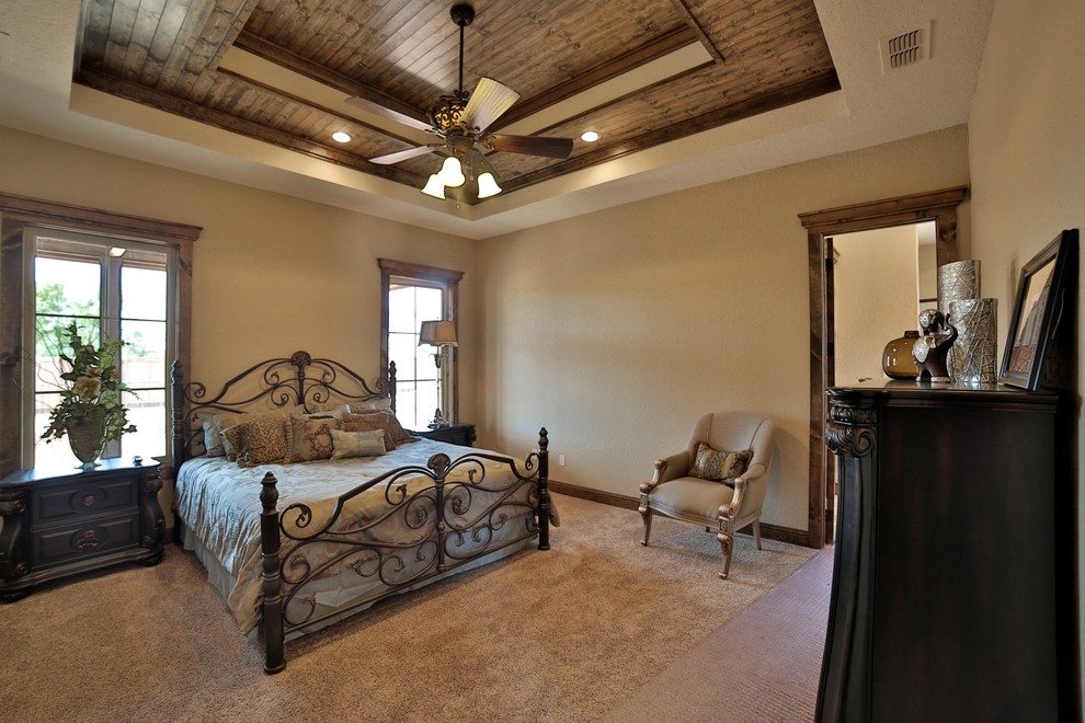 This is an example of a mid-sized mediterranean master bedroom in Dallas with beige walls and carpet.