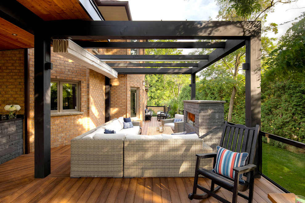 Photo of a transitional backyard deck in Toronto with with fireplace and an awning.