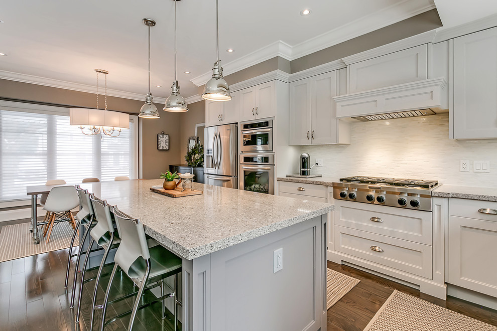 Open concept kitchen - mid-sized transitional l-shaped open concept kitchen idea in Toronto with an undermount sink, shaker cabinets, white cabinets, quartz countertops, white backsplash, matchstick tile backsplash, stainless steel appliances, an island and multicolored countertops