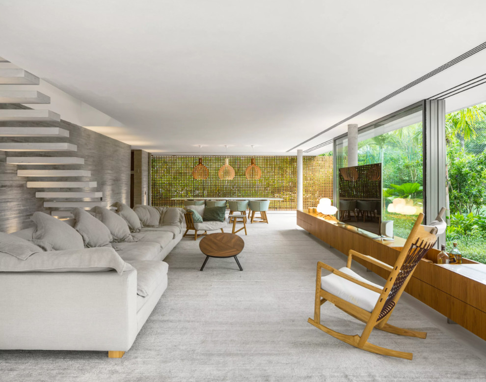 This is an example of an expansive modern formal open concept living room in Madrid with grey walls, a freestanding tv, grey floor and carpet.