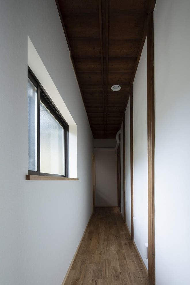 Esempio di un piccolo ingresso o corridoio con pareti bianche, pavimento in legno massello medio, pavimento marrone e soffitto in legno