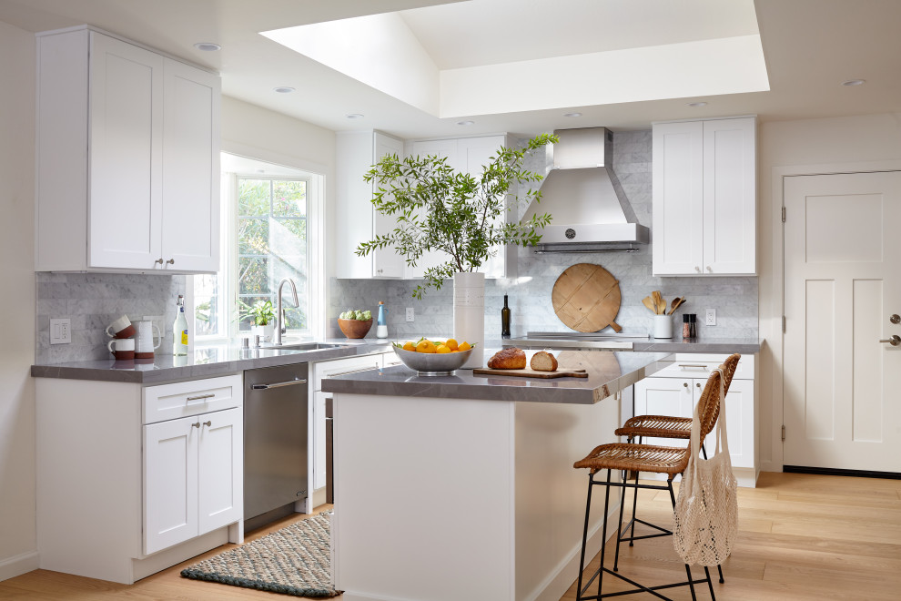 Inspiration for a large contemporary l-shaped kitchen pantry in San Francisco with an undermount sink, shaker cabinets, white cabinets, grey splashback, stainless steel appliances, light hardwood floors, with island, grey benchtop, quartz benchtops, marble splashback and multi-coloured floor.