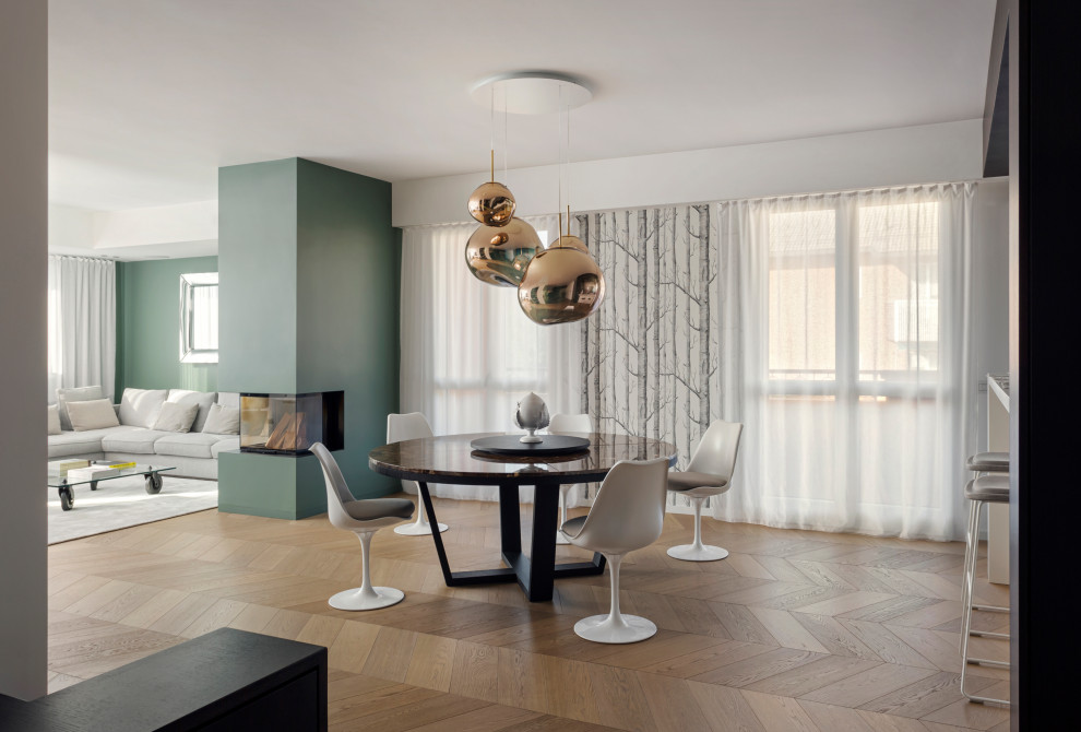 Geräumiges Modernes Esszimmer mit grüner Wandfarbe, braunem Holzboden, Tunnelkamin, verputzter Kaminumrandung, beigem Boden und Tapetenwänden in Mailand