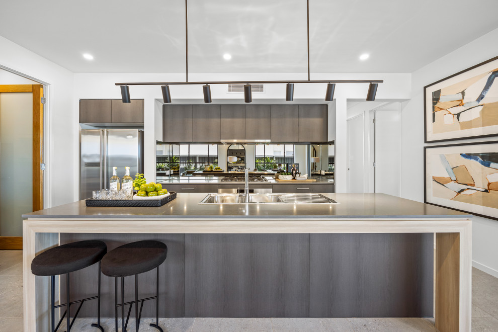 На фото: параллельная кухня в современном стиле с накладной мойкой, плоскими фасадами, серыми фасадами, зеркальным фартуком, островом, серым полом и серой столешницей с