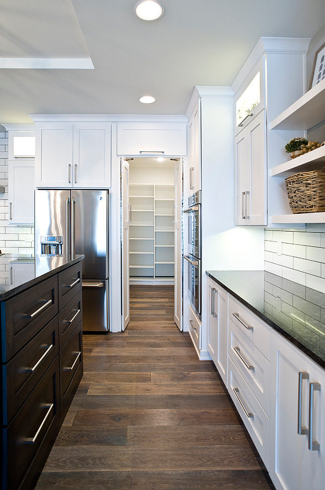 Eat-in kitchen - large transitional l-shaped dark wood floor and brown floor eat-in kitchen idea with an undermount sink, shaker cabinets, white cabinets, granite countertops, white backsplash, subway tile backsplash, stainless steel appliances and an island