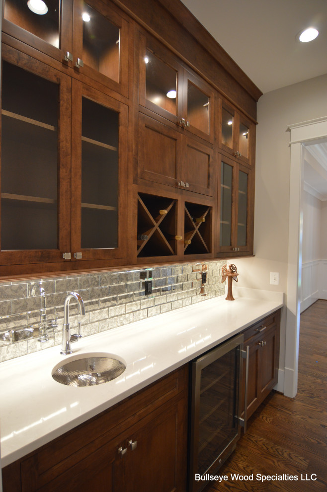 Photo of a mid-sized traditional u-shaped open plan kitchen in DC Metro with an undermount sink, shaker cabinets, medium wood cabinets, quartz benchtops, white splashback, medium hardwood floors, multiple islands, brown floor and white benchtop.