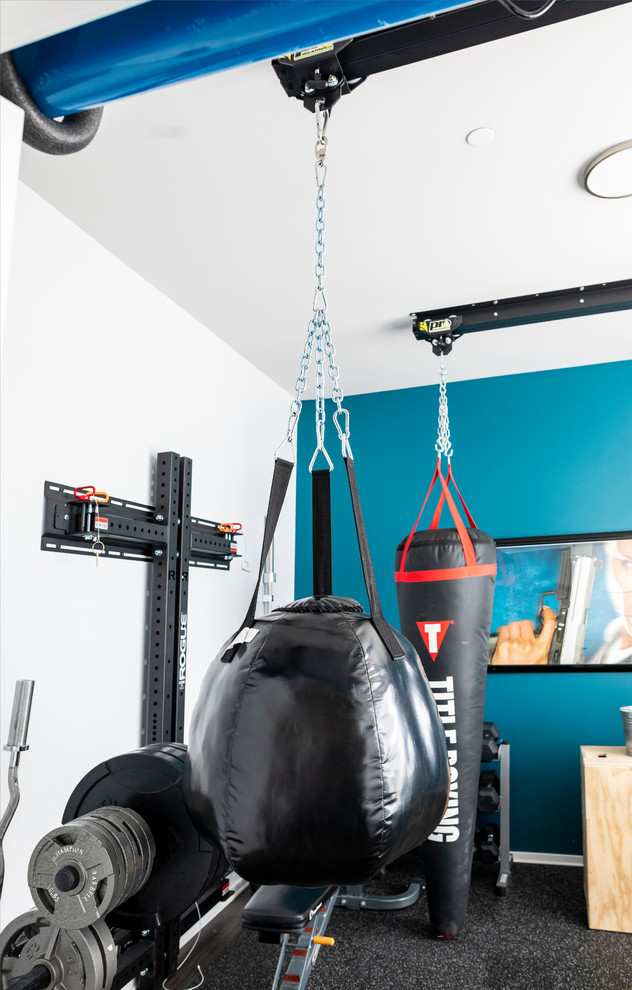 This is an example of a mid-sized modern home weight room in Seattle with blue walls, cork floors and black floor.