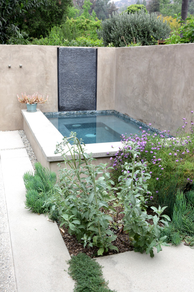Großer, Halbschattiger Moderner Gartenwasserfall im Frühling, hinter dem Haus mit Betonboden und Steinzaun in Los Angeles