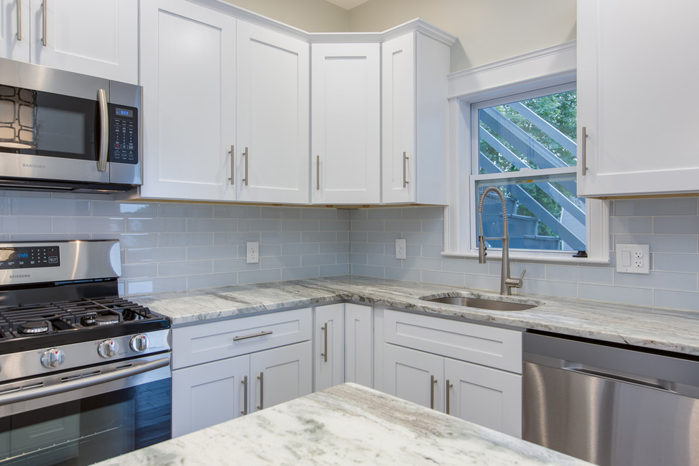 Mid-sized transitional l-shaped dark wood floor and brown floor enclosed kitchen photo in Boston with an undermount sink, shaker cabinets, white cabinets, marble countertops, gray backsplash, subway tile backsplash, stainless steel appliances, an island and white countertops