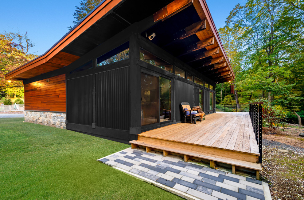 На фото: одноэтажный, деревянный, коричневый частный загородный дом среднего размера в стиле ретро с крышей-бабочкой и отделкой планкеном с